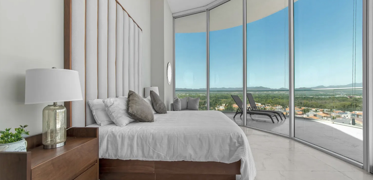 Staged bedroom with floor-to-ceiling windows overlooking the valley