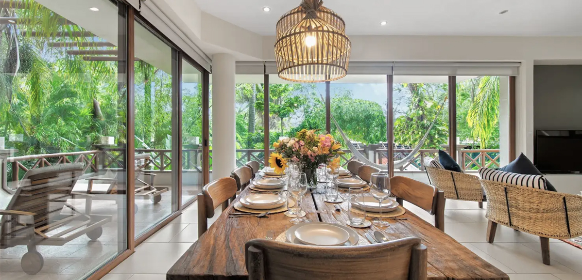 Staged dining room of a vacation rental with tropical terrace views
